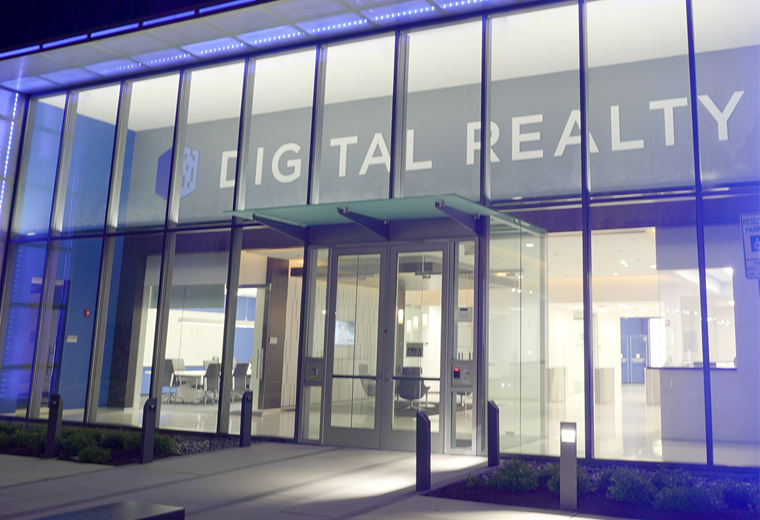 Modern glass-front office building with illuminated “Digital Realty” signage entrance