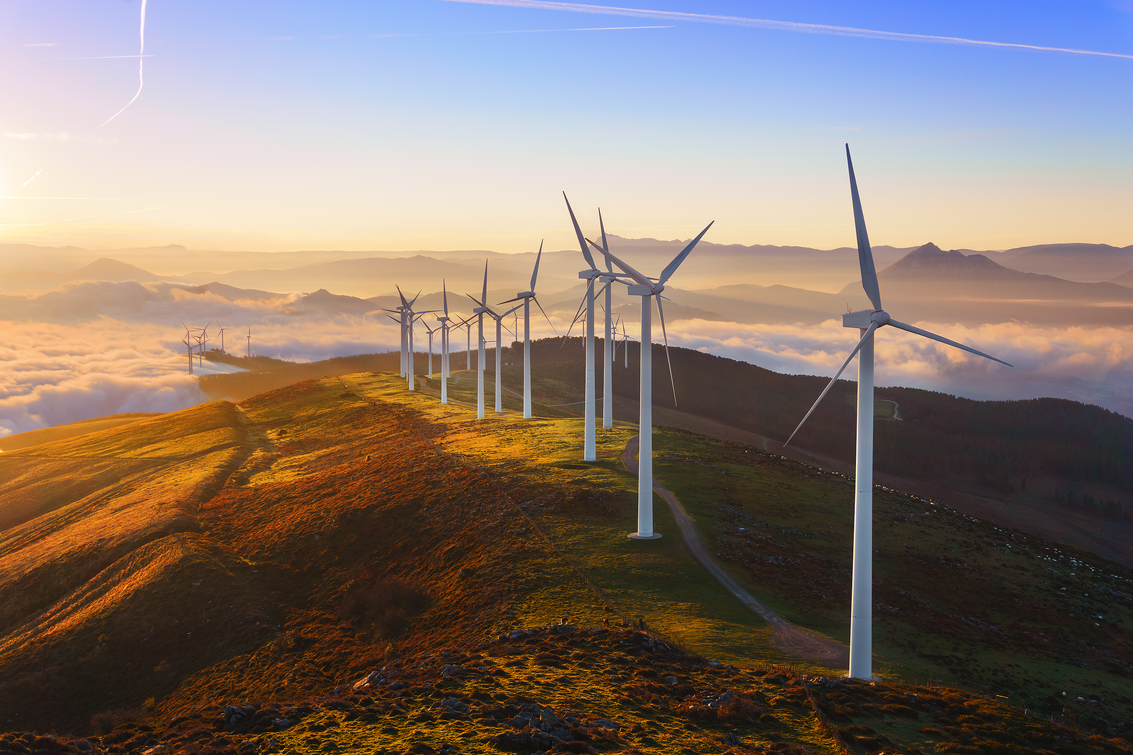 wind trubines on top of a hill during the sunset