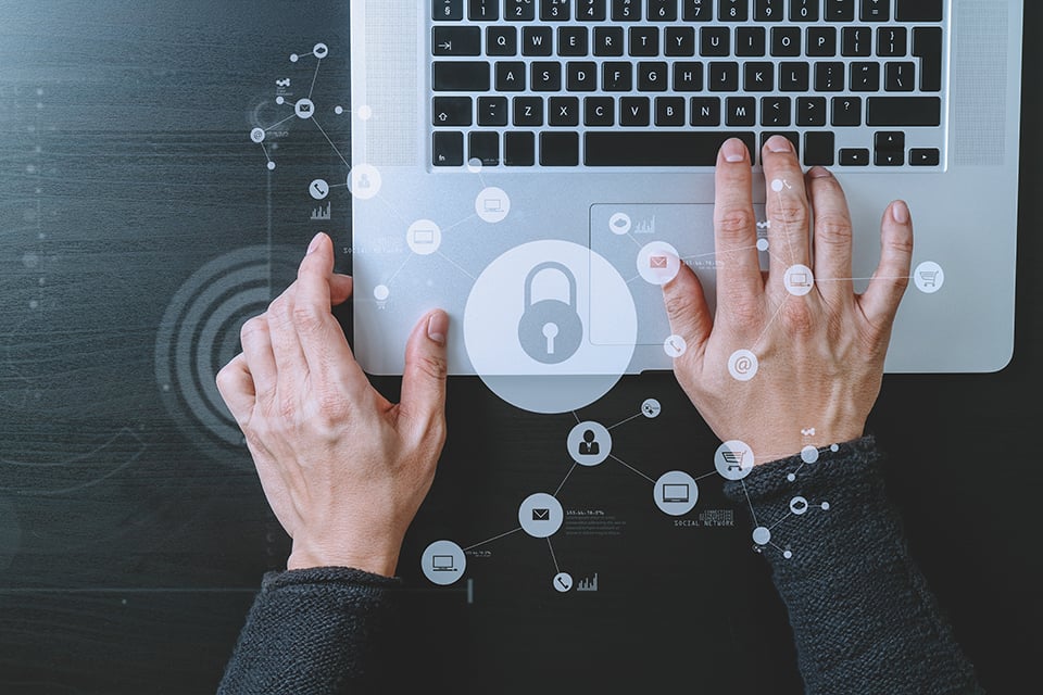 Hands typing on a laptop with a digital lock icon overlay, representing online security and data protection.